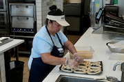 An employee makes pretzels at an Auntie Anne's and Cinnabon store in Livermore, Calif., Thursday, March 28, 2024. She's among hundreds of thousands of California fast-food workers who will be paid at least $20 an hour starting Monday, April 1. (AP Photo/Terry Chea)